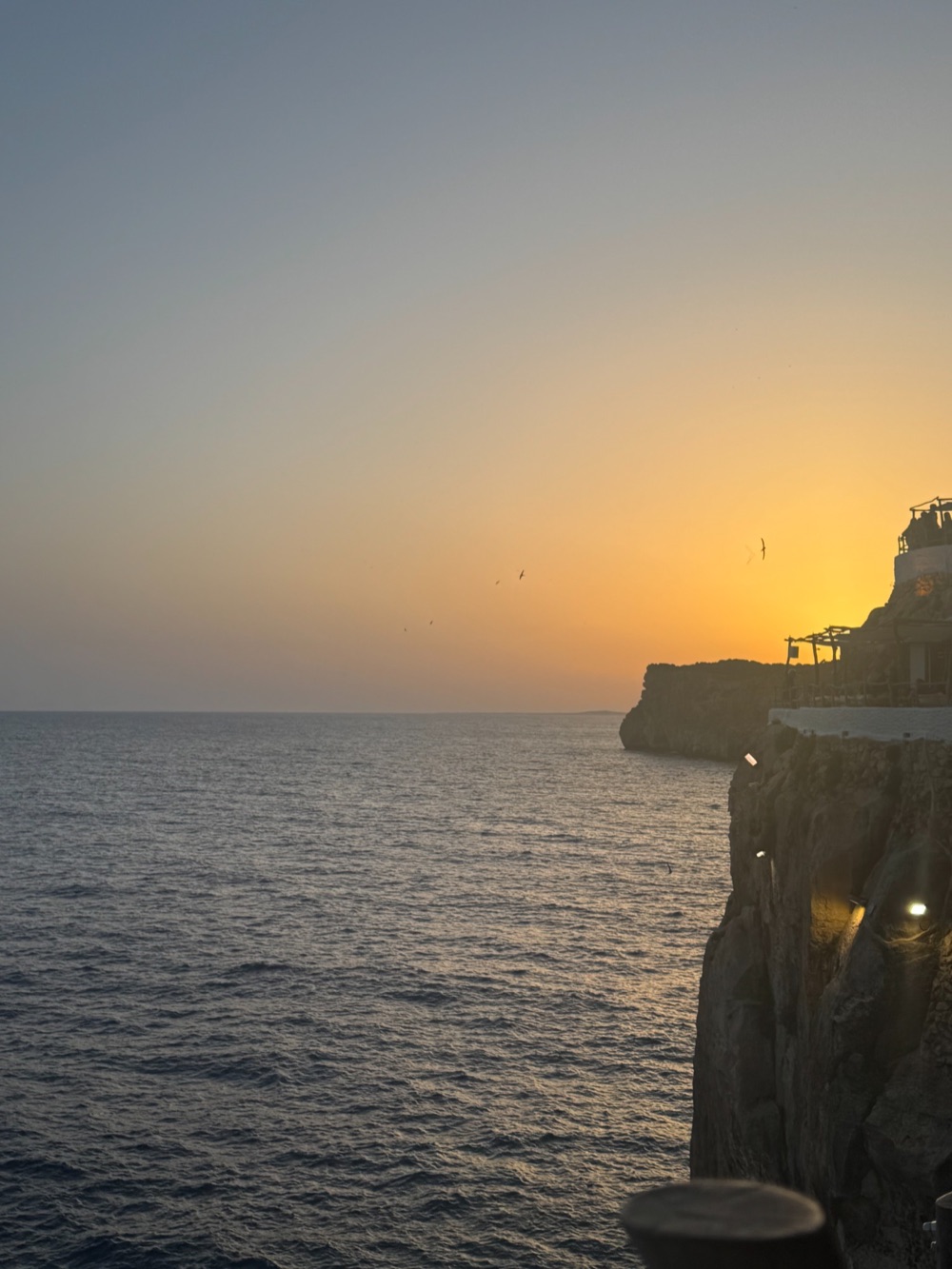 Golden sunset over the sea beside a rocky cliff